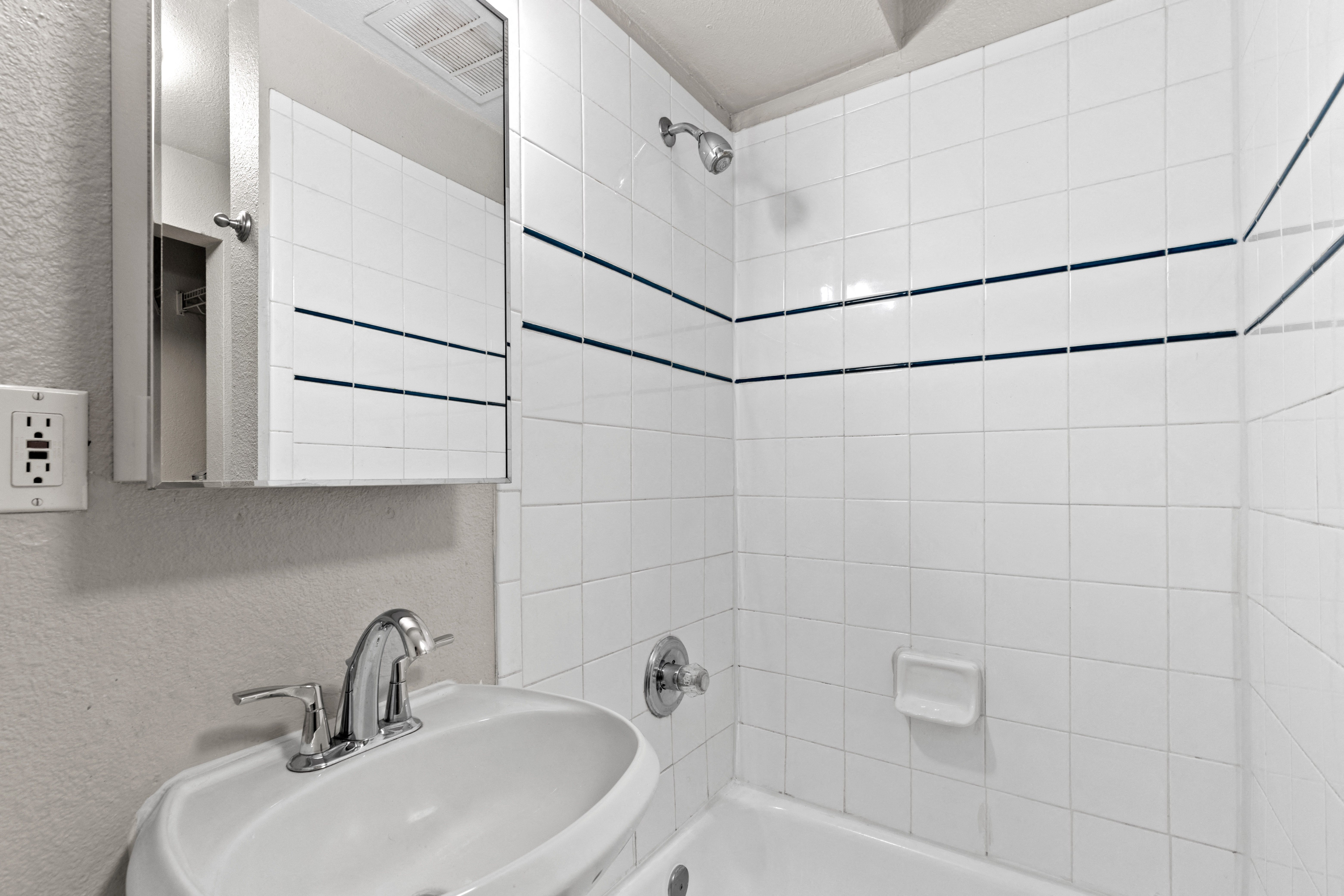 a bathroom with a sink and a tub and a mirror